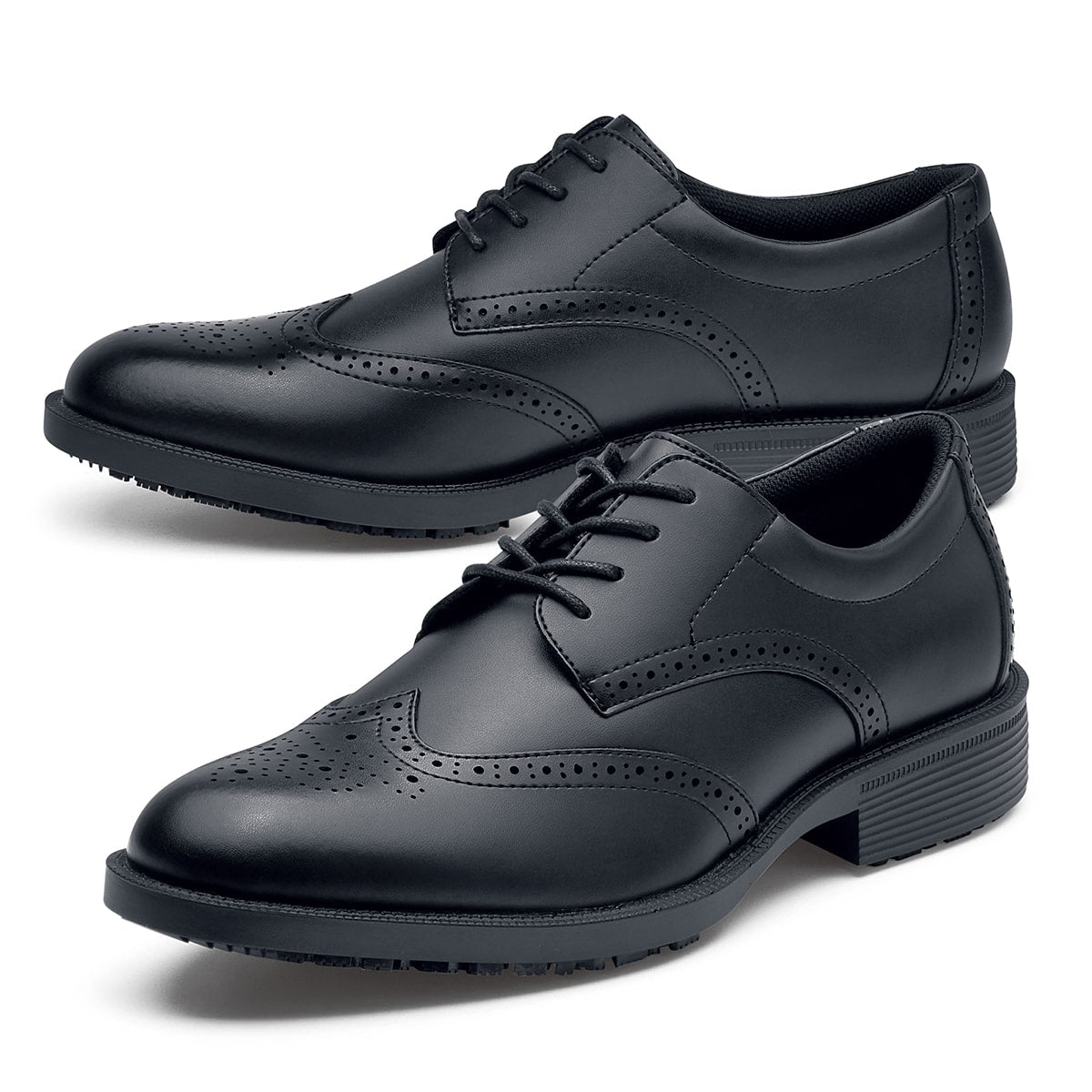 The Executive Wing Tip IV from Shoes For Crews, is an slip resistant dress shoe with a water resistant breathable leather upper to provide industry leading levels of grip and durability, pair seen from the left side, emphasised on the tip of the left shoe.
