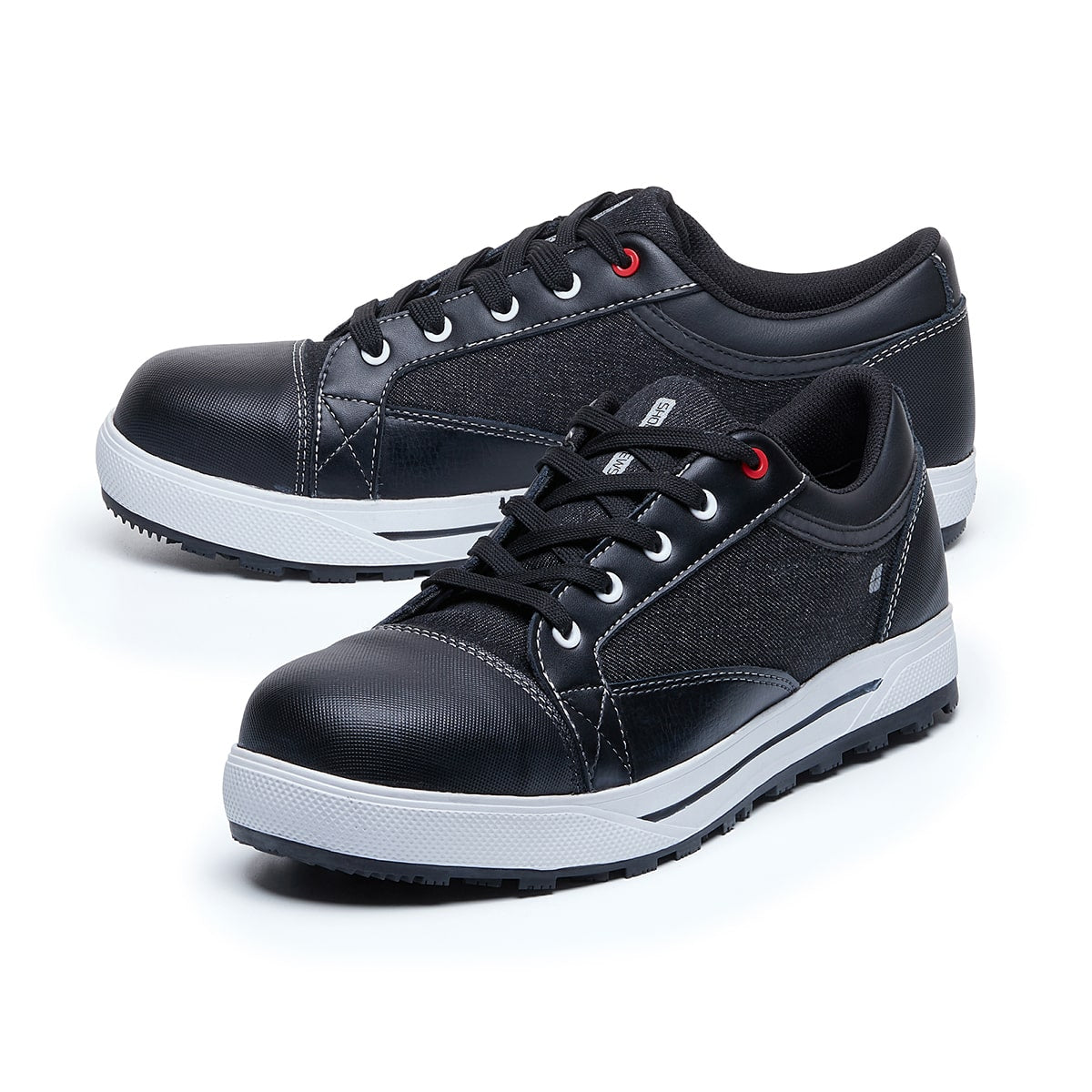 The Fergus Denim from Shoes For Crews is an slip-resistant safety shoe with a waterproof leather upper and a nanocomposite toe cap (200 joules), pair seen from the left side, emphasised on the tip of the left  shoe.